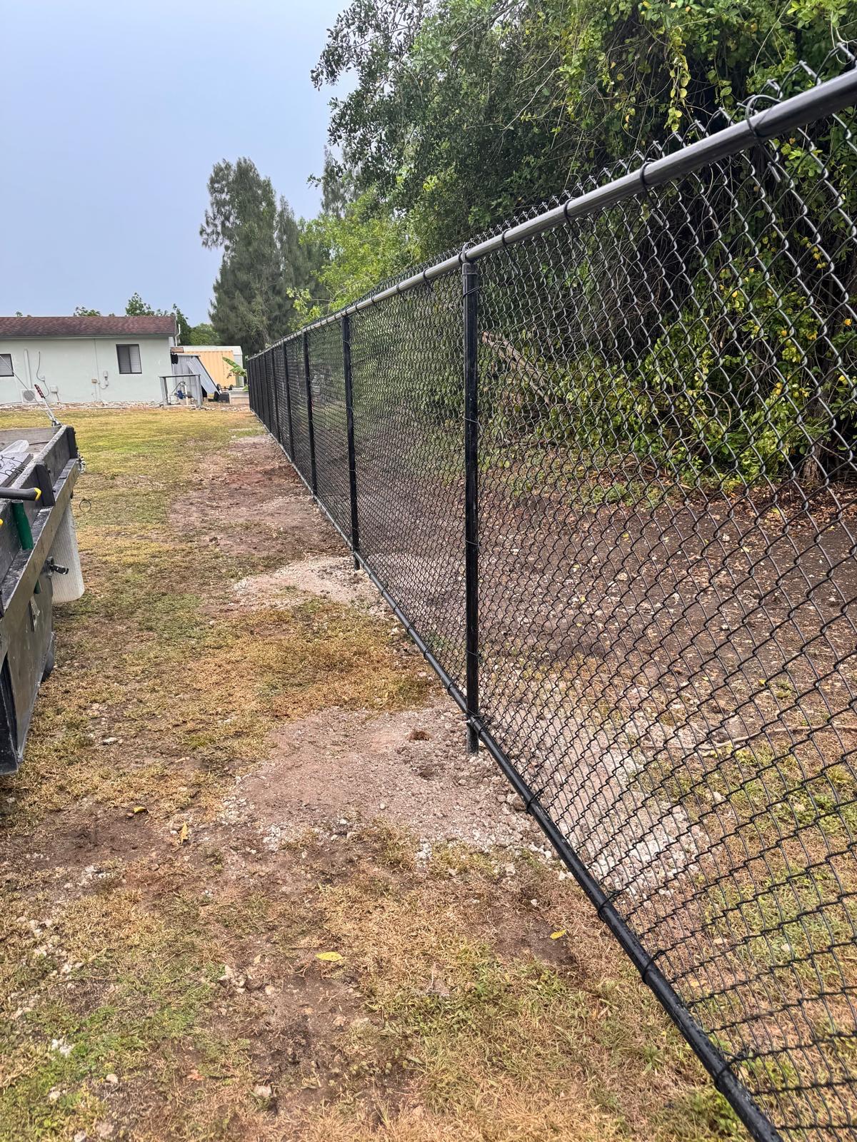 Black chain link fence installation along property line